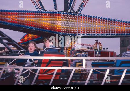 Funfair sur le front de mer d'Helensburgh, en Écosse, avec des enfants sur Twister. Banque D'Images