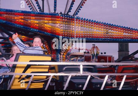 Funfair sur le front de mer d'Helensburgh, en Écosse, avec des enfants sur Twister. Banque D'Images