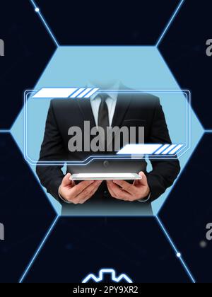 Homme d'affaires en costume noir debout et tenant la tablette dans deux mains. Lueur provenant de l'affichage du périphérique. Image de style futuriste avec brillant coloré. Design numérique. Banque D'Images