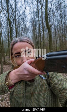 Portrait d'une femme avec un fusil de chasse debout dans un bois Banque D'Images