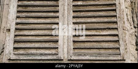 Vieux volets en bois sur la fenêtre. Architecture en bois antique. Sécher le bois avec de la peinture décolorée bruissant. Enveloppe et poussière. Couleur naturelle. Seuil de fenêtre, bandes horizontales et lattes. Banque D'Images