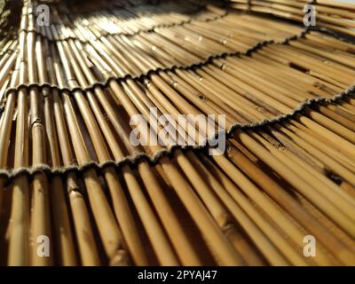 Une literie en paille, une nappe ou un petit tapis posé sur une table et photographié de côté. La douce lumière du soleil du soir se reflète sur les tiges. Certains bâtons sont cassés, les fils et les cordes sont tressés Banque D'Images