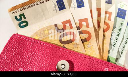 Billets en euros. Monnaie européenne sur fond blanc. Un sac à main ou un sac à main de couleur rose vif avec un bouton en métal, à partir duquel l'argent est réparti dans un ventilateur. Billets de 5, 10, 20, 50 et 100 Banque D'Images