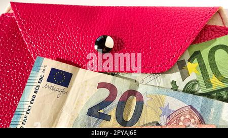 Billets en euros. Monnaie européenne sur fond blanc gros plan. Portefeuille ou sac à main en rose vif avec un bouton métallique brillant. Billets de banque de la Banque centrale pour 20 et 100 euros Banque D'Images