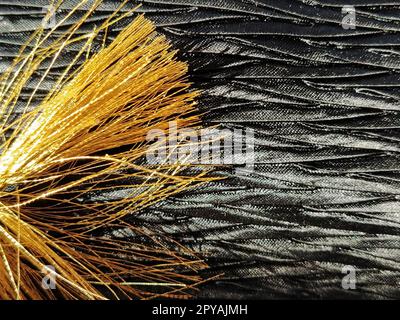 pampille dorée sur tissu texturé noir de soie. Tissu scintillant et fils de soie. gros plan Banque D'Images