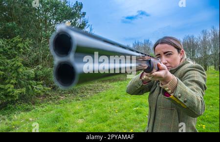 Une femme de plus de trente ans avec un fusil de chasse en gros regardant le canon Banque D'Images