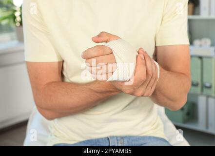 Homme enveloppé à la main dans un bandage médical à l'hôpital, en gros plan Banque D'Images