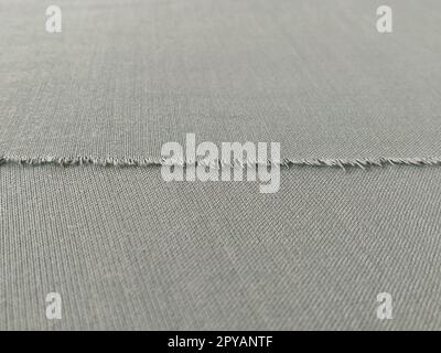 Bord déchiré de tissu de laine fine en vert ou bleu. Fils lâches au bord d'un morceau de textile. Gros plan. Fond tissé. Couleur pastel vert calme Banque D'Images