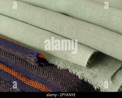 Tissu plié vert clair et noir-gris avec rayures orange et bleu foncé. Décoration intérieure. Habiller les tissus dans un style décontracté. Matériau dense pour rideaux d'intérieur et finition de meubles Banque D'Images