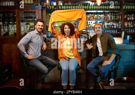 Des amis du millénaire enthousiastes se réunissent au bar pour assister à un match de football Banque D'Images