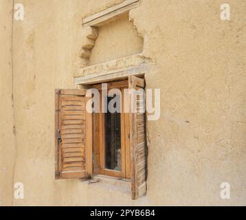 Ancienne fenêtre rustique en bois avec volets dans le mur de la maison égyptienne traditionnelle en brique de boue Banque D'Images