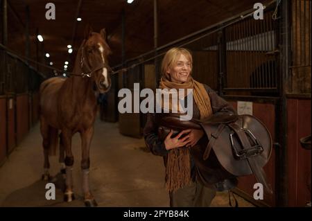 Cavalier femelle marchant avec harnais en stable Banque D'Images