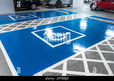 Parking réservé aux conducteurs handicapés dans un supermarché ou un centre commercial. Parking pour personnes à mobilité réduite. Panneau pour fauteuil roulant peint sur le parking. Parking handicapés bleu et blanc. Banque D'Images