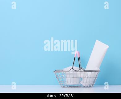 Tubes en plastique blanc, bocaux dans un panier en métal miniature, récipients pour produits cosmétiques. Publicité et promotion Banque D'Images