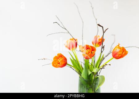 Un très beau bouquet printanier dans un vase vert se dresse sur une table sur une nappe en lin, tulipes pivoines orange. Fête des mères, 8 mars, Saint-Valentin. Place pour une inscription. Banque D'Images