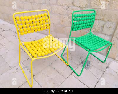 Deux chaises sont alignées sur le trottoir de marbre. Chaises de massage vides jaunes et vertes avec boutons. Dubrovnik, Croatie. Intérieur créatif non standard. Banque D'Images