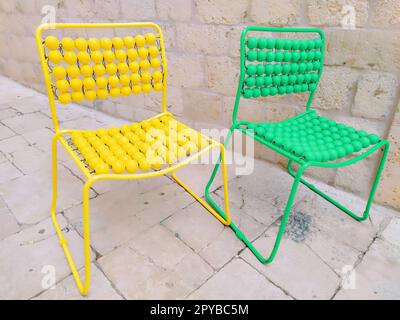 Deux chaises sont alignées sur le trottoir de marbre. Chaises de massage vides jaunes et vertes avec boutons. Dubrovnik, Croatie. Intérieur créatif non standard. Banque D'Images