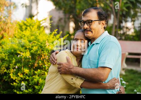 Femme âgée indienne heureuse embrassant ou embrassant son mari en se tenant étroitement avec l'espace de copie - concept de compagnon, sécurisé et confortable Banque D'Images
