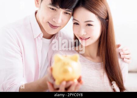 Couple heureux tenant Piggybank et faisant des économies pour l'avenir Banque D'Images