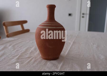 Vue de face d'un ancien pichet en céramique antique non peint sur une nappe blanche. Pichet en argile pour boire du vin ou de l'eau. Banque D'Images