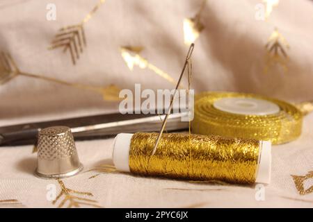 Bobine de fil d'or et ciseaux avec Thimble sur tissu métallique Banque D'Images