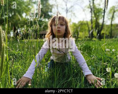 la fille est assise dans l'herbe et tend ses bras vers l'avant Banque D'Images