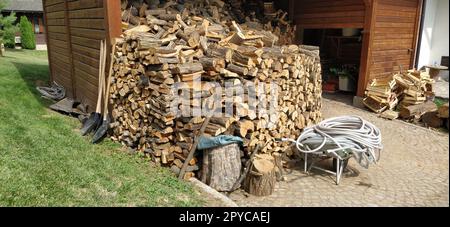 Bois de chauffage dans la grange. Autour de la buanderie se trouvent du bois de chauffage, des tuyaux en caoutchouc, des ustensiles ménagers. Restaurant arrière-cour dans le style ethno. Architecture en bois Banque D'Images