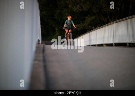 Jolie, jeune femme avec son vélo tout-terrain allant pour un tour au-delà des limites de la ville, obtenant la dose quotidienne de cardio Banque D'Images