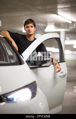 Parking souterrain / garage (image colorée DOF peu profonde) - jeune conducteur masculin avec sa petite voiture électrique de ville Banque D'Images