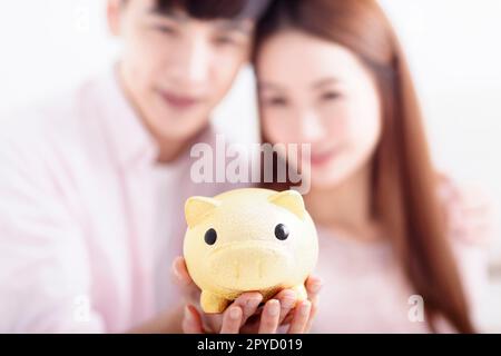 Couple heureux tenant Piggybank et faisant des économies pour l'avenir Banque D'Images