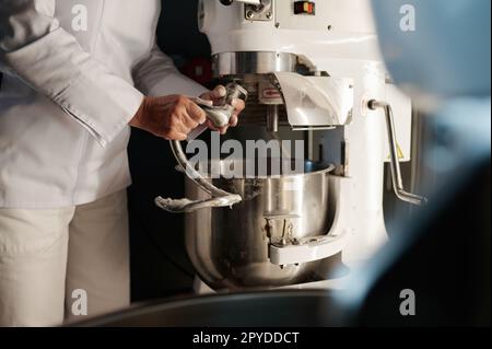 Boulanger femme travaillant dans une cuisine professionnelle avec un mélangeur de pâte à la boulangerie Banque D'Images