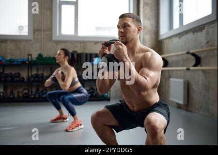 Homme et femme avec un bon physique tenant une lourde cloche de bouilloire Banque D'Images