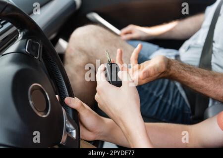 vue rognée de l'adolescent tenant la clé de voiture à côté du père dans l'automobile, image de stock Banque D'Images