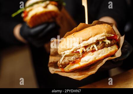 Homme gants noirs tenant les mains de Burger Juicy Burger Fermez le hamburger appétissant. Banque D'Images