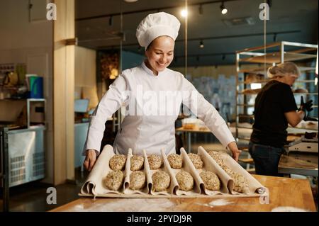 Femme boulangère préparant des petits pains sucrés avec des graines de sésame Banque D'Images