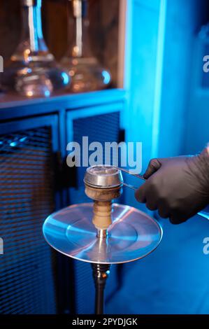 Gros plan homme faisant du narguilé mettant des cubes de charbon chaud sur le bol à tabac Banque D'Images