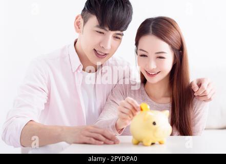 Un jeune couple asiatique tient à Piggybank et fait des économies pour l'avenir Banque D'Images