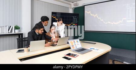 Groupe de gens d'affaires en costume analysent les informations de stock dans la salle de réunion. Réunion de l'équipe de dirigeants d'entreprise dans un bureau moderne avec ordinateur portable, tablette, téléphone portable sur la table. Banque D'Images