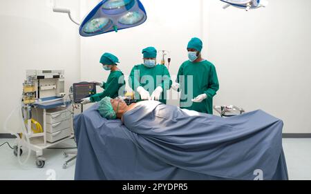 Groupe de chirurgiens et infirmière en uniforme de robe verte chirurgicale effectuant l'opération chirurgicale dans la salle d'opération. Banque D'Images