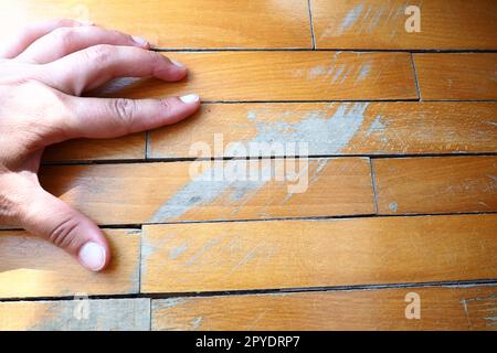 Les anciens parquets rayés doivent être entretenus. le parquet est endommagé par des rayures résultant d'une utilisation prolongée. Les mains du maître sont endommagées par le sol Banque D'Images