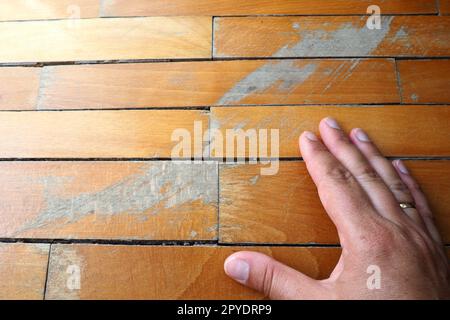 Les anciens parquets rayés doivent être entretenus. le parquet est endommagé par des rayures résultant d'une utilisation prolongée. Les mains du maître sont endommagées par le sol Banque D'Images