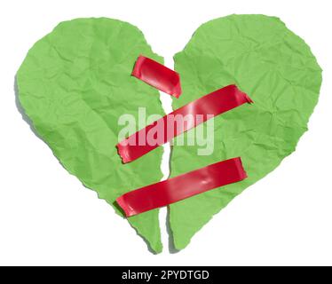 Cœur déchiré en papier froissé vert fixé avec du ruban électrique rouge sur un fond blanc Banque D'Images