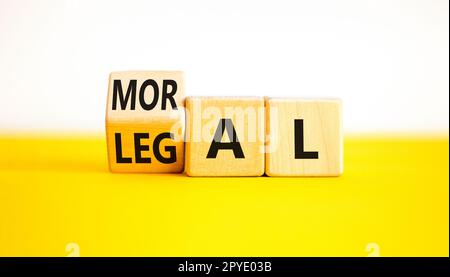 Symbole juridique ou moral. L'homme d'affaires tourne des cubes en bois et change le mot Légal à moral sur un magnifique fond blanc de table jaune. Business et L Banque D'Images