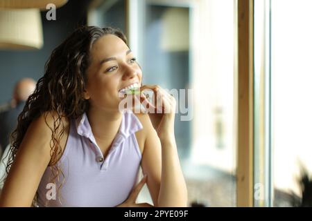 Femme mangeant du kiwi dans un restaurant Banque D'Images