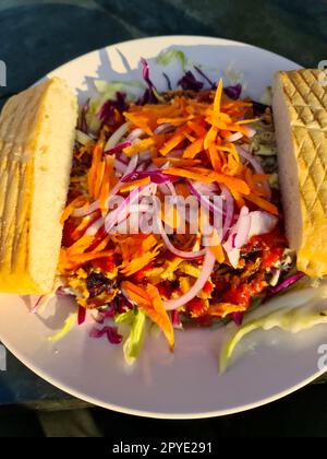 Vue de dessus d'une salade de kebab fraîche avec deux tranches de pain et soleil sur l'assiette. Banque D'Images