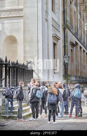 Un groupe de jeunes touristes avec guide à l'extérieur de Senate House, Université de Cambridge, Angleterre. Banque D'Images