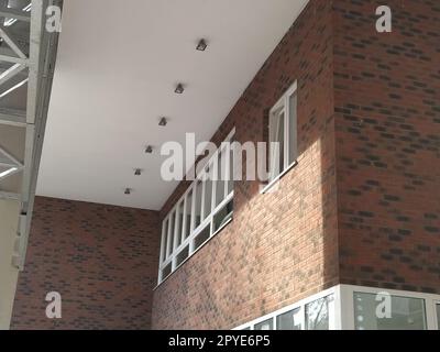 Extérieur de la nouvelle école. Nouvelles fenêtres blanches en plastique. Brun à la mode - brique de parement rouge. Arche métallique avec auvent. Plafonnier. Entrée de l'école. Serbie, Sremska Mitrovica. Banque D'Images