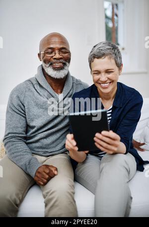 Nous adorons regarder des vidéos en ligne ensemble. un couple affectueux utilisant une tablette tout en se relaxant sur le canapé à la maison. Banque D'Images