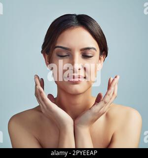 Ma peau est tout simplement parfaite. Photo en studio d'une jeune femme sur fond gris. Banque D'Images