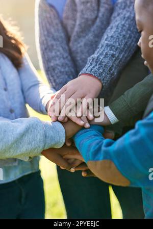 Unir les jeunes esprits. un groupe d'enfants d'école élémentaire méconnus se joint les mains dans un caucus à l'extérieur. Banque D'Images